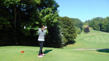 A woman watches her ball in the air from the tee off