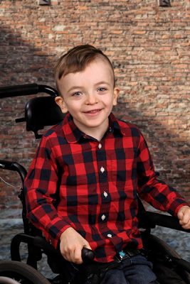 Hunter in a red shirt, smiles from his wheelchair.