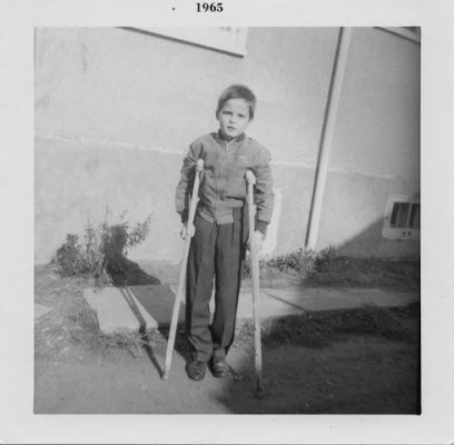Image of Glen as a child, holding two crutches