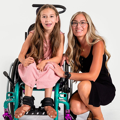 Brooke sits in her wheelchair and her mom kneels beside her