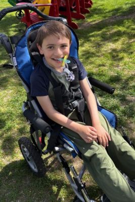 Grayson sitting in a wheelchair in a park