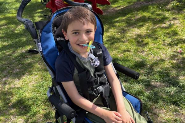 Grayson sitting in a wheelchair in a park - thumbnail