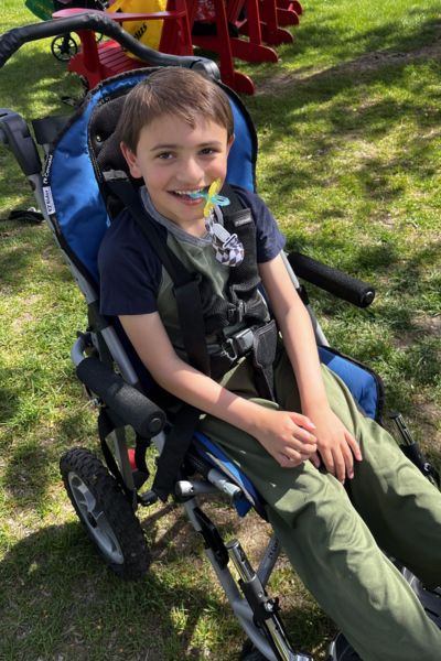Grayson sitting in a wheelchair in a park