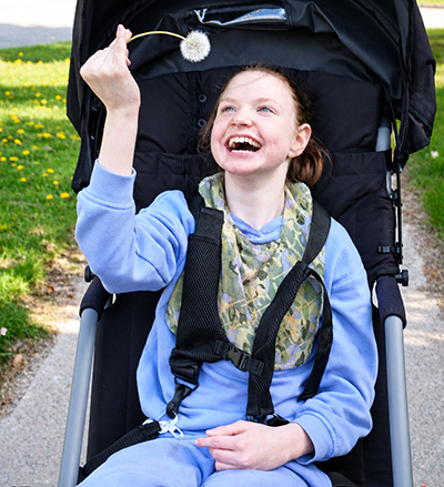 Rilynn holding a dandelion puff and smiling.