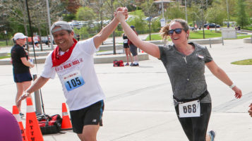 A man and woman cross the finsih line clasping hands in the air